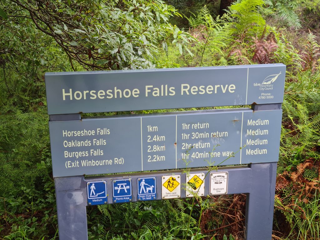 Sign at the Oaklands Rd entry to Horseshoe Falls walking track detailing the walking distance and estimated times to the 3 main falls along the track