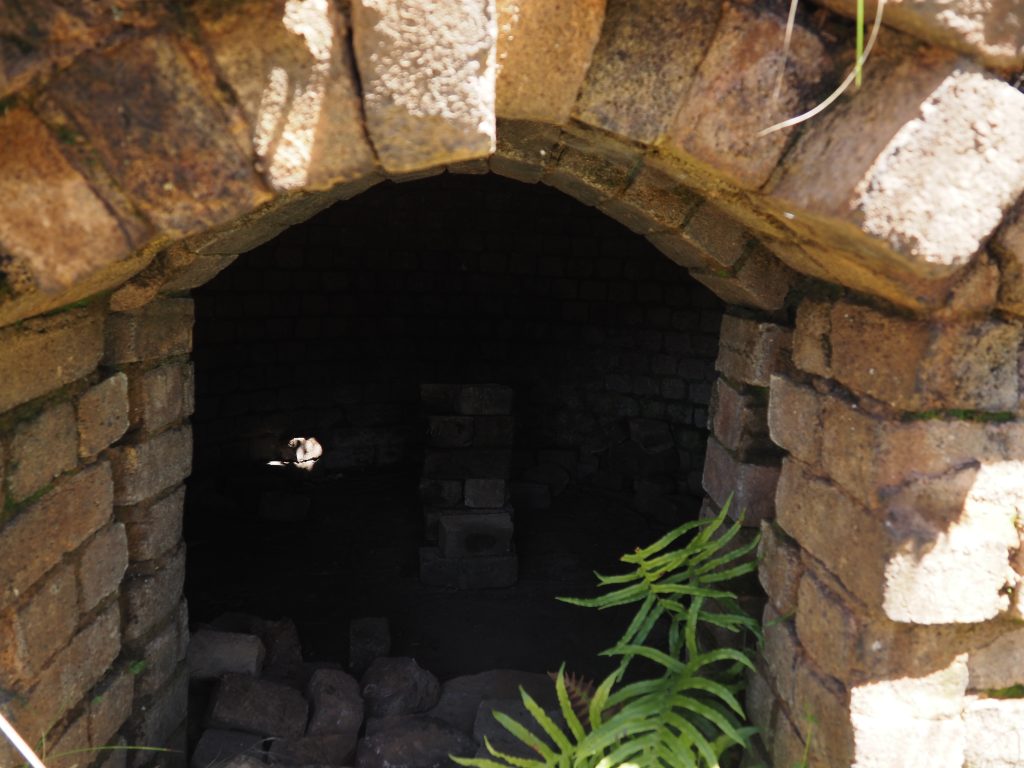 close up of interior of the kiln from doorway, showing large open space and stacked bricks in the middle of the floor