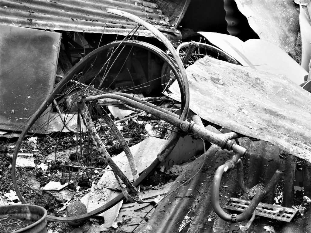 Black and White image of a scorched and twisted bicycle in the rubble of a burnt house after the Grose Valley fire