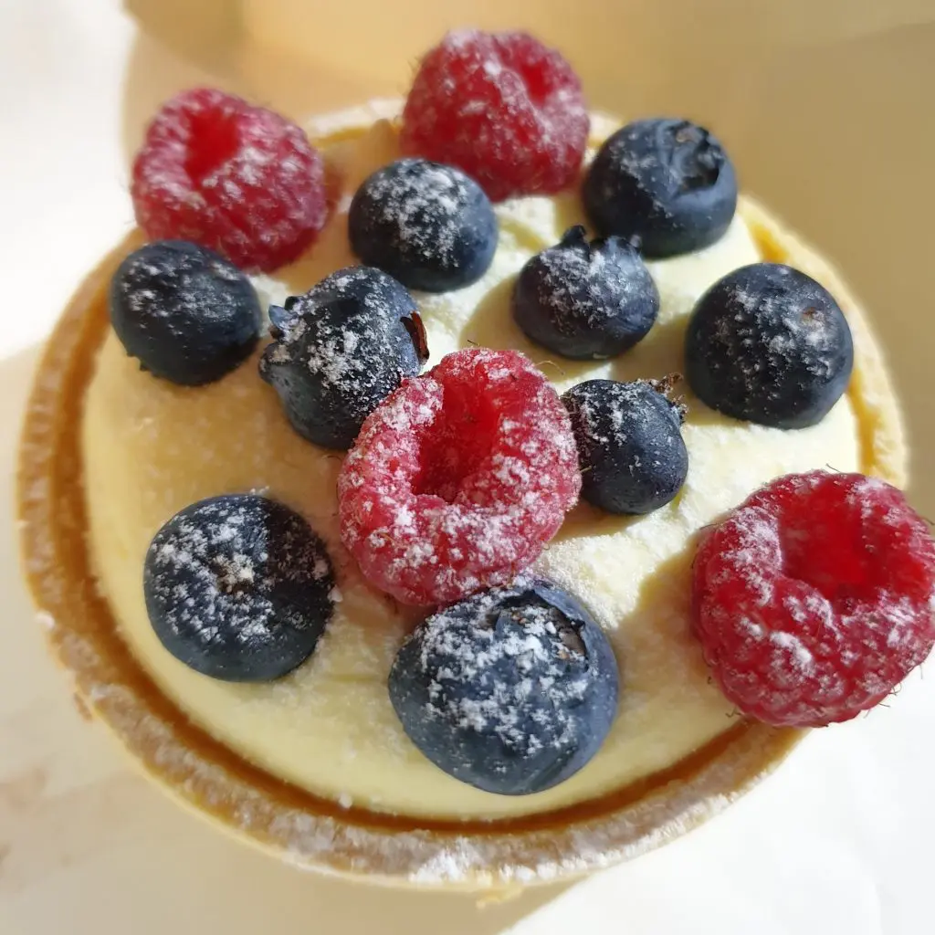 Marscapone Tart from Schwarzes Bakery in Wentworth Falls. A circular pasty similar to a pie crust is filled with marscapone cream and topped with fresh Blueberries and Raspberries with a dusting of icing sugar.