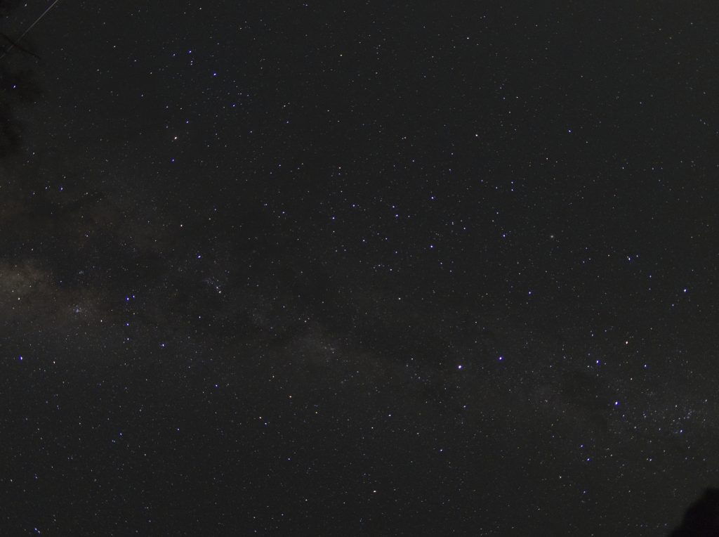 Astrophotography image of the Milky Way on the night of a meteor shower. A meteor can be seen streaking across the image in the top left corner