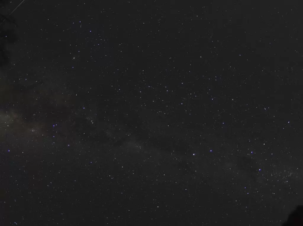 Astrophotography image of the Milky Way on the night of a meteor shower. A meteor can be seen streaking across the image in the top left corner