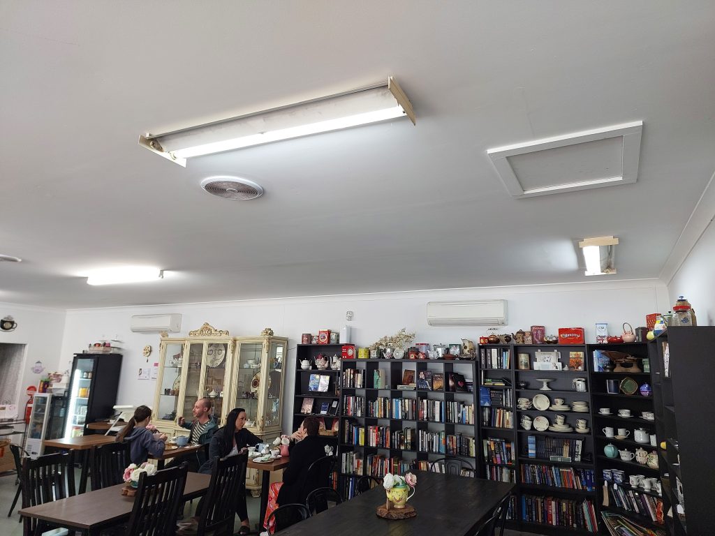 Inside Chapters and Leaves teahouse at Faulconbridge, a number of tables can be seen in the room, with shelving against the wall displaying books and bric a brac